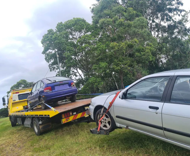 A car being towed by a flatbed truck, representing car disposal in Brisbane.
