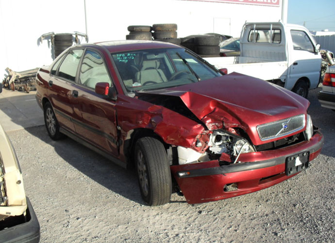 Damaged red car in a parking lot, highlighting the need for Cash for Junk Cars in Brisbane.
